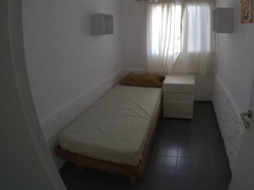 Habitación pequeña con cama y ventana en Depto. próximo al Centro y Rio San Antonio en Villa Carlos Paz