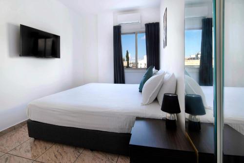 a white bedroom with a large bed and a window at Urban Condo 43 - 1 Bdr in Nicosia