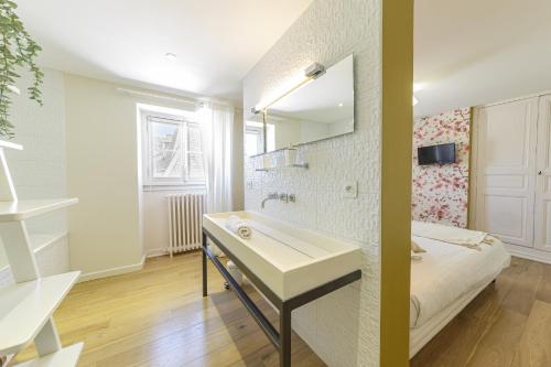a bathroom with a sink and a bed and a mirror at Chambre Crémant - Maison Bossoreil in Angers