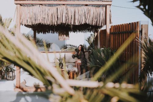 a woman sitting on a couch in a room with plants at Margarita Hotel in Firostefani