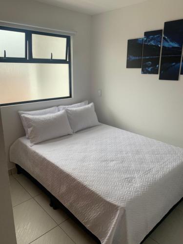 uma cama branca num quarto com uma janela em Bajo la Luna El Carmen de Viboral em Carmen de Viboral