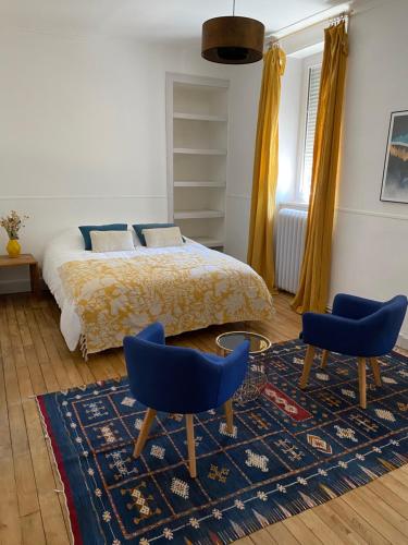 - une chambre avec un lit et deux chaises bleues dans l'établissement Maison chaleureuse avec piscine, 