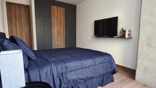 a bedroom with a bed and a flat screen tv at Acogedor y moderno departamento in Mexico City