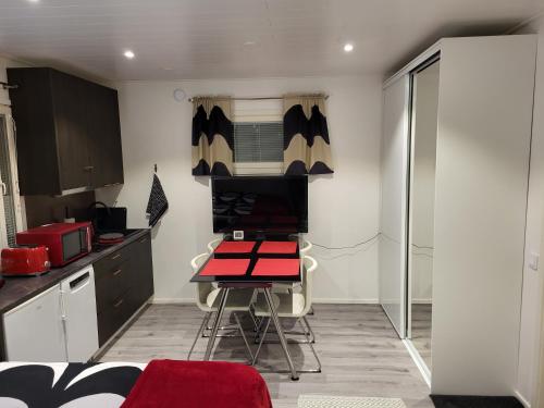 uma pequena cozinha com uma secretária e uma mesa vermelha em Guest House Koskenkylä em Rovaniemi