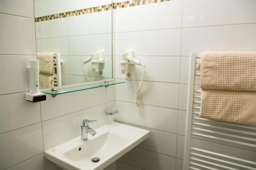 a white bathroom with a sink and a phone at Hotel Vinothek Schwarzer Adler in Ottensheim