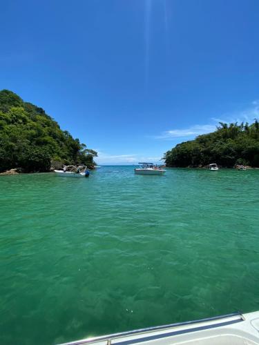 two boats in a body of water with trees at Passeios de lancha em Angra dos Reis in Angra dos Reis