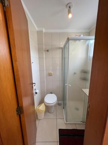 uma casa de banho com um WC e uma cabina de duche em vidro. em A 400m da BEIRA MAR no centro apartamento completo com box em Capão da Canoa