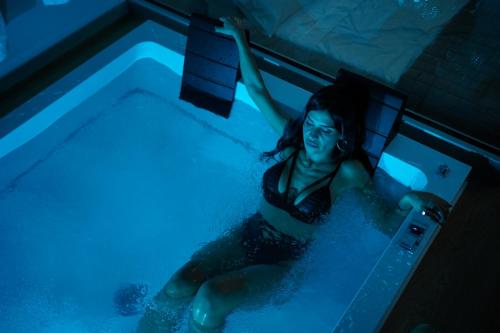 a woman is sitting in a swimming pool at ZOE LUXURY SUITES in Catania