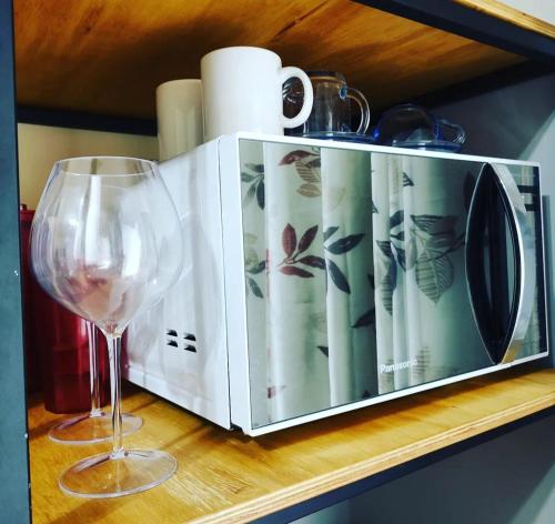 a microwave sitting on a shelf next to a wine glass at Loft/kit estilo industrial encantador c/garagem pv in Belém