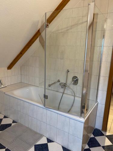 a bath tub with a glass shower in a bathroom at FEWO Eggenstein beim KIT in Eggenstein-Leopoldshafen