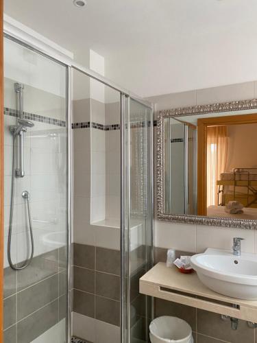 bagno con doccia, lavandino e specchio di Hotel Ravello Adults Only a Rimini