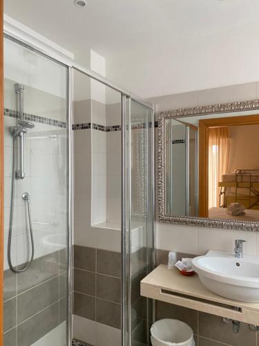 uma casa de banho com um chuveiro, um lavatório e um espelho. em Hotel Ravello em Rimini