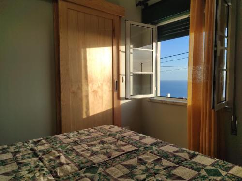 a bedroom with a quilt on a bed and a window at Casa da Guida in Angra do Heroísmo