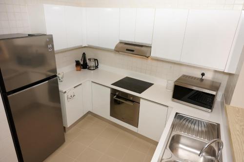 a kitchen with white cabinets and a stainless steel refrigerator at Palmar One Bedroom with Private Beach! in Dubai