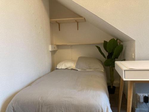 - un lit avec deux oreillers dans une petite chambre dans l'établissement Le Voyageur, à Besançon