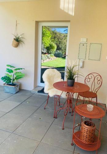 a patio with two tables and two chairs and a window at La Romély in Arzier