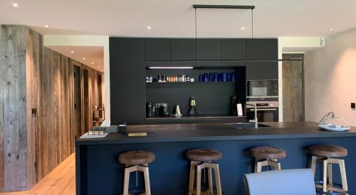 une cuisine avec un îlot bleu avec tabourets dans l'établissement Xanadu, à Megève