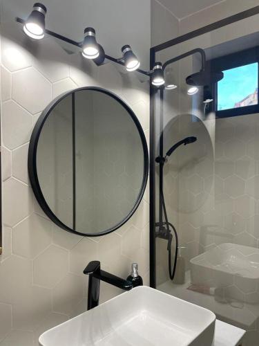 a bathroom with a sink and a mirror and a shower at FLH - Nana's apartment in Sibiu