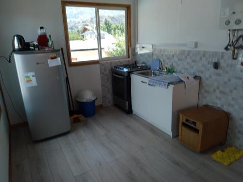 a kitchen with a refrigerator and a sink and a window at Calfu in Chile Chico
