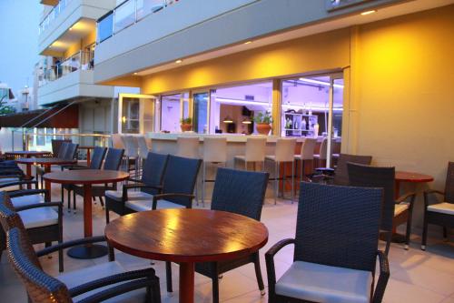 a restaurant with tables and chairs and a bar at Michel Apartments in Kos