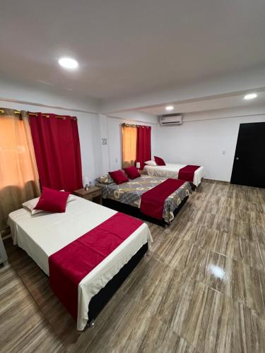 プロビデンシアにあるPOSADA VILLA BRYANのベッド3台と赤いカーテンが備わるホテルルーム
