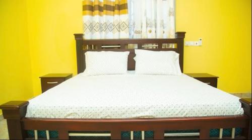 um quarto com uma cama grande e paredes amarelas em Extended Stay em Adentan