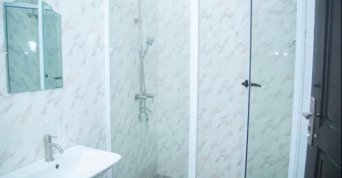 baño blanco con ducha y lavamanos en Extended Stay, en Adentan