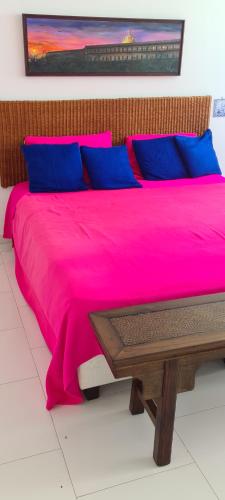 ein Bett mit einer rosa Decke und einem Holztisch in der Unterkunft Hermoso apartamento de lujo en Morros 3 , Piso 5 con vista al mar in Cartagena de Indias