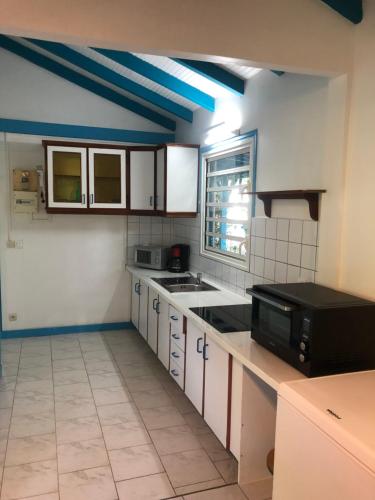 a kitchen with white cabinets and a black microwave at Rêves de mer in Deshaies