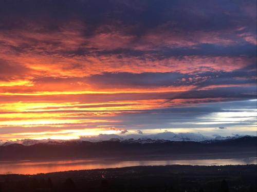 a sunset with clouds and mountains in the background at La Romély in Arzier