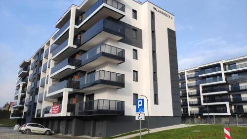 un condominio bianco con un cartello di parcheggio di fronte di Apartament "Marianki" Jagiełły 3 a Świecie