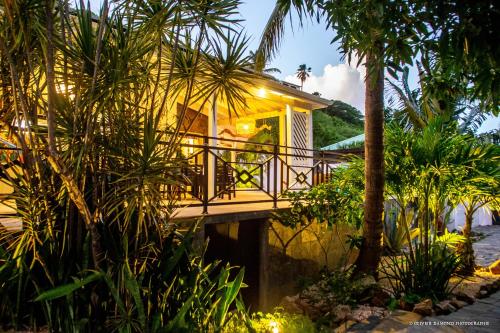 a house with a balcony with palm trees in front of it at Villa Fleur de Pirate in Orient Bay