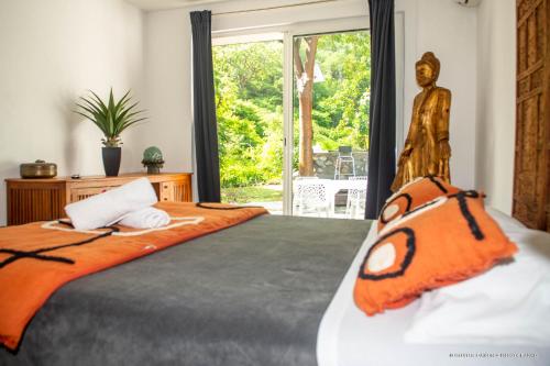 una camera da letto con un grande letto e un piumone arancione di VILLA « FLEUR DE PIRATE » a Saint Martin