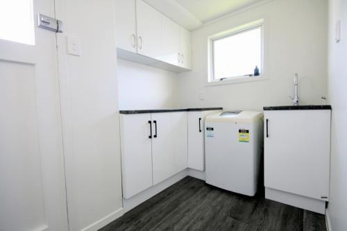 a white kitchen with white cabinets and a window at Opunake Break - Opunake Holiday Home in Opunake