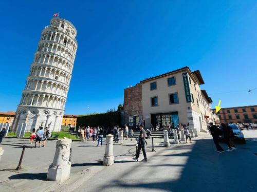 a group of people walking in front of the leaning tower at Under the Tower in Pisa