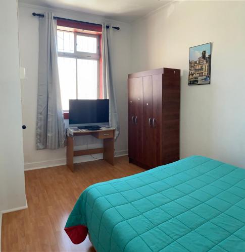 a bedroom with a bed and a desk with a television at Barros Borgoño 1 Departamento in Valparaíso