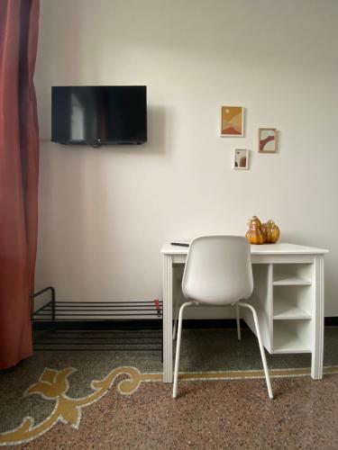 einen weißen Schreibtisch mit einem Stuhl und einem TV an der Wand in der Unterkunft CASA AMEDEO in Genua