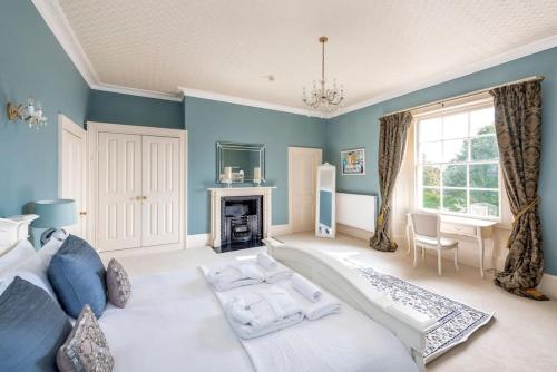 sypialnia z niebieskimi ścianami, łóżkiem i kominkiem w obiekcie The Manor Holcombe Luxury House Pool & Hot-tub w mieście Holcombe