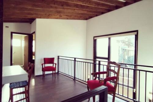 een balkon met rode stoelen en een witte tafel en raam bij Casa Zurich in Pichilemu
