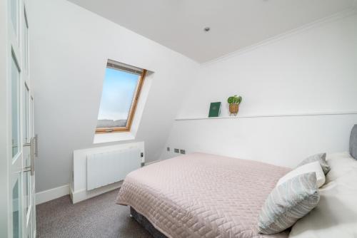 a white bedroom with a bed and a window at Camden Town Apartment in London