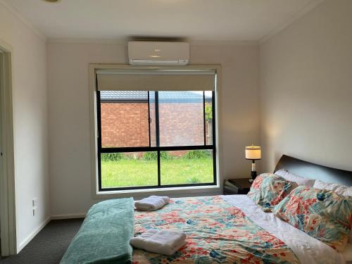 um quarto com uma cama e uma grande janela em 4 Beds-Whole House-Black Knight Way-Kuranjang-Less than 30 minutes From Melbourne international airport em Melton