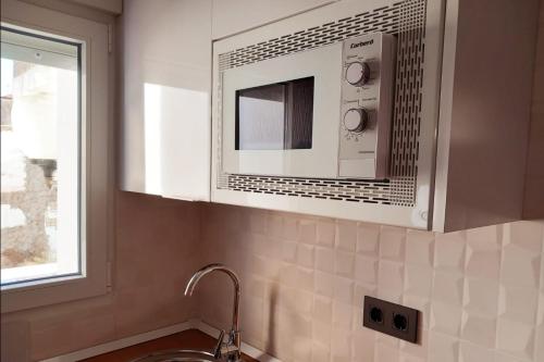 eine Mikrowelle über einer Spüle in einer Küche in der Unterkunft Apartamento de la Haya, junto al Teatro Romano in Merida