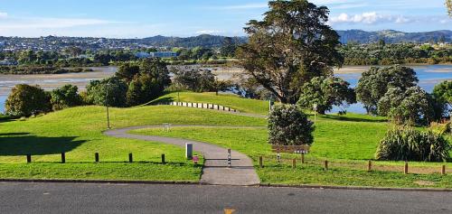 a park with a winding road next to a river at Pohutukawa Lodge by Orewa Beach in Orewa