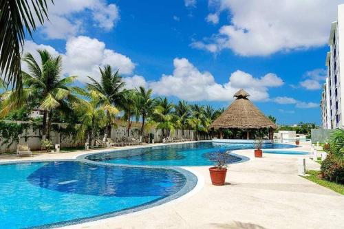 una piscina en un complejo con palmeras en Departamento de dos habitaciones con increíble alberca y amenidades Y-406 en Cancún