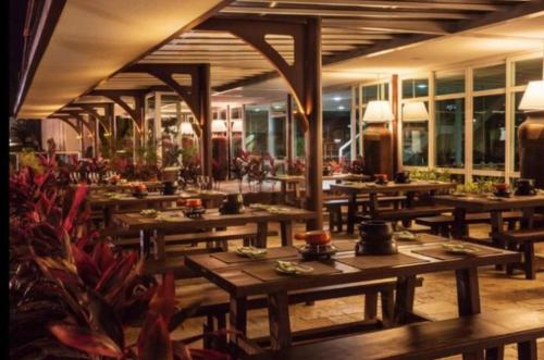 ein Restaurant mit Holztischen in einem Zimmer mit Fenstern in der Unterkunft Villa Hípica Resort- Flat 203 in Gravatá