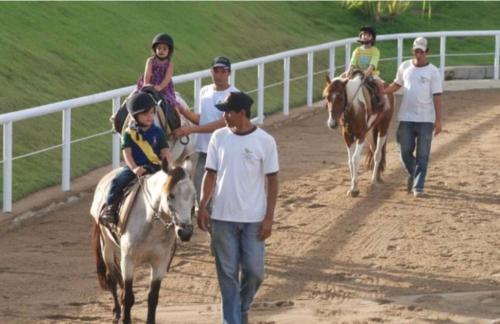 eine Gruppe von Menschen, die auf einer Strecke reiten in der Unterkunft Villa Hípica Resort- Flat 203 in Gravatá