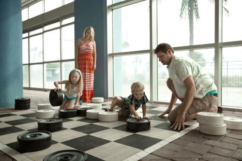a man and two children playing on a chessboard at Bay View Resort Myrtle Beach in Myrtle Beach