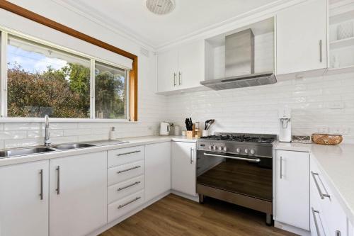 a white kitchen with a sink and a stove at Seaview Cottage and pool - Wifi and Linen included in Inverloch