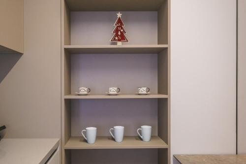 a shelf with cups and a christmas tree on it at Two Steps Apartments Tirana in Tirana