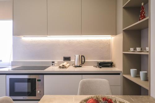 a kitchen with white cabinets and a microwave and a table at Two Steps Apartments Tirana in Tirana